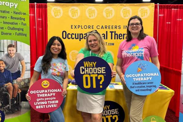 NBCOT staff standing in front of the Why Choose OT exhibit booth