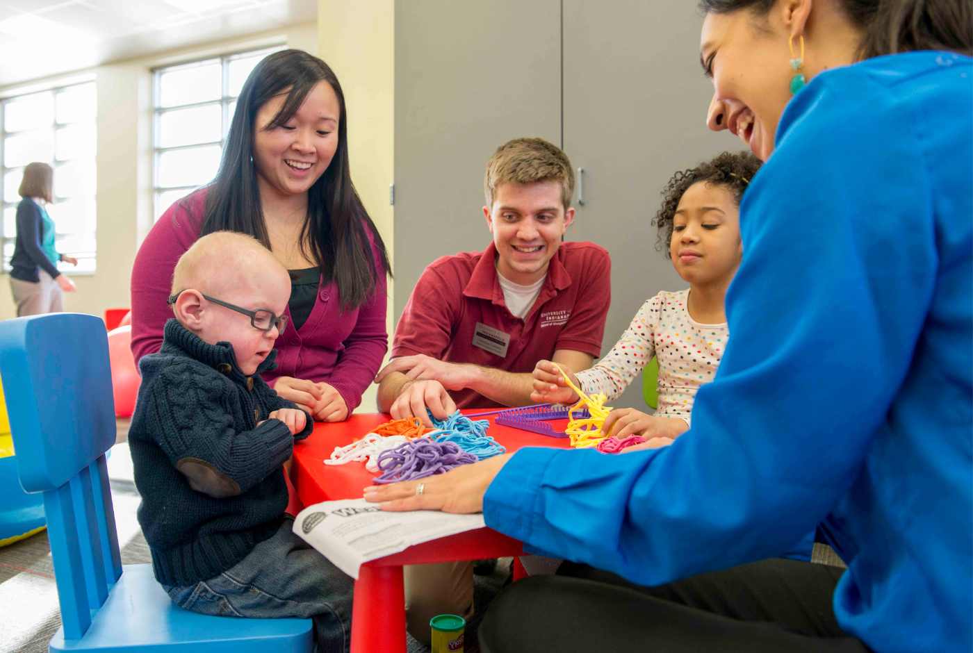 Two children sitting at a table with occupational therapists participating in play.