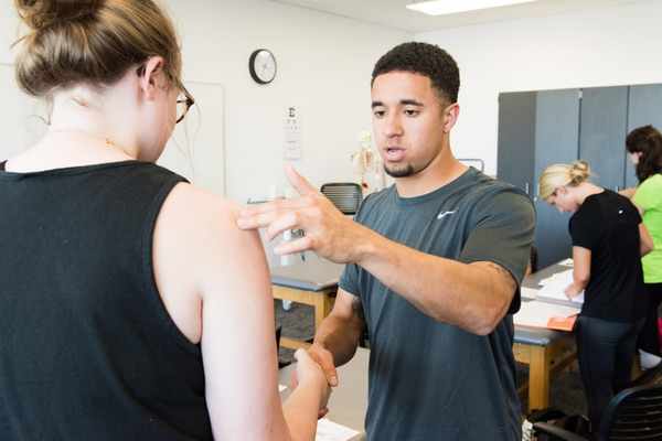 Two occupational therapy students practicing therapy techniques on each other