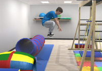 A young boy jumps in the air inside a sensory gym.