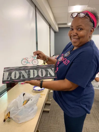 A woman shows off two art projects.
