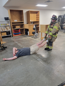 A firefighter drags a man across the floor by his feet.