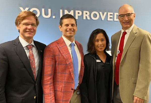 Three men and one woman smile at the camera.