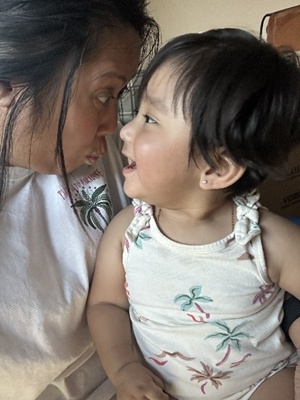 Mickie and a child are facing each other and making a silly face.