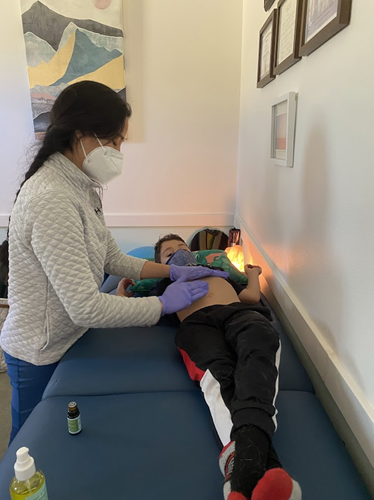 A child lies on an exam table while Dr. Smith presses on the child's belly.
