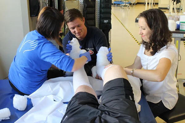 Rebecca Hammad and two colleagues bandage a patient's legs.