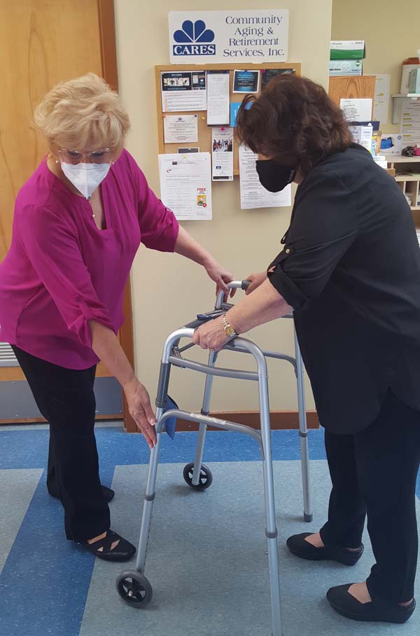 Dr. Vanessa Dazio, OTR, helps an elderly female client position her walker.